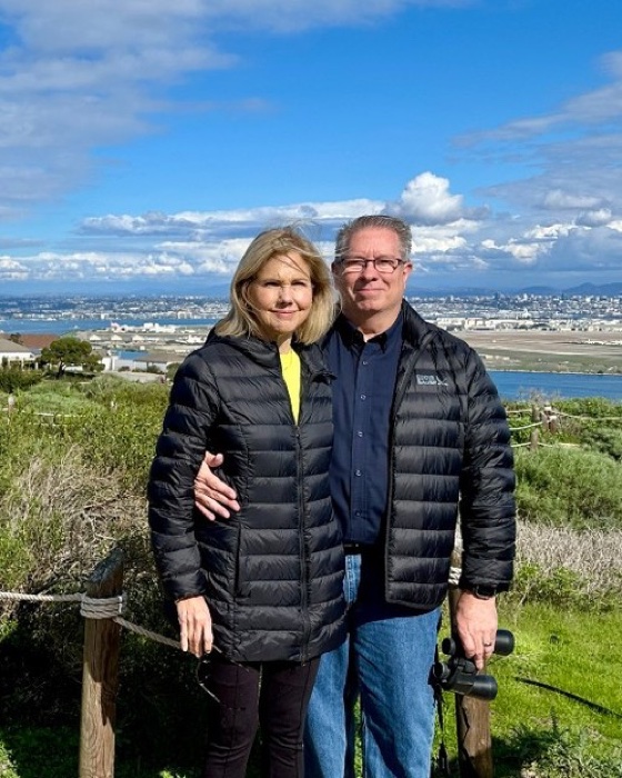 Jeff Hunt and his wife outdoors with a city and bay behind them